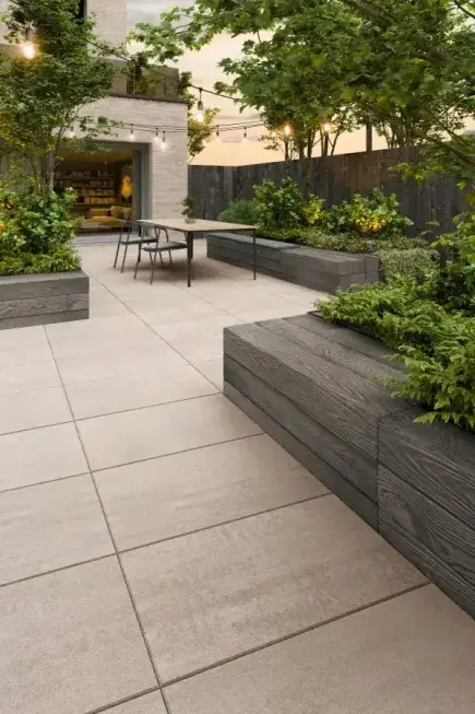 A backyard with Blu Grande concrete slabs by Techo-Bloc in a Caffè Crema color and wood concrete planters