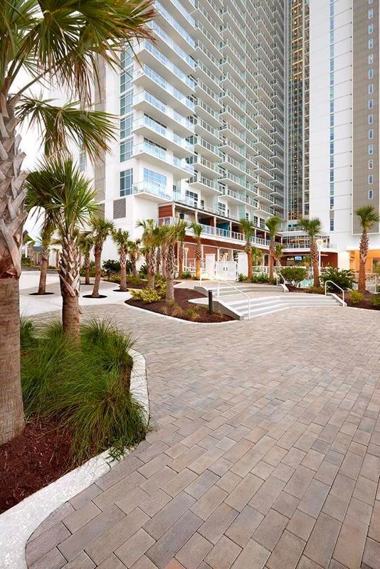 Un terrasse spacieuse &#xE0; Myrtle Beach entour&#xE9;e de palmiers mettant en vedette les dalles commerciales Para de Techo-Bloc dans la couleur gris champlain.
