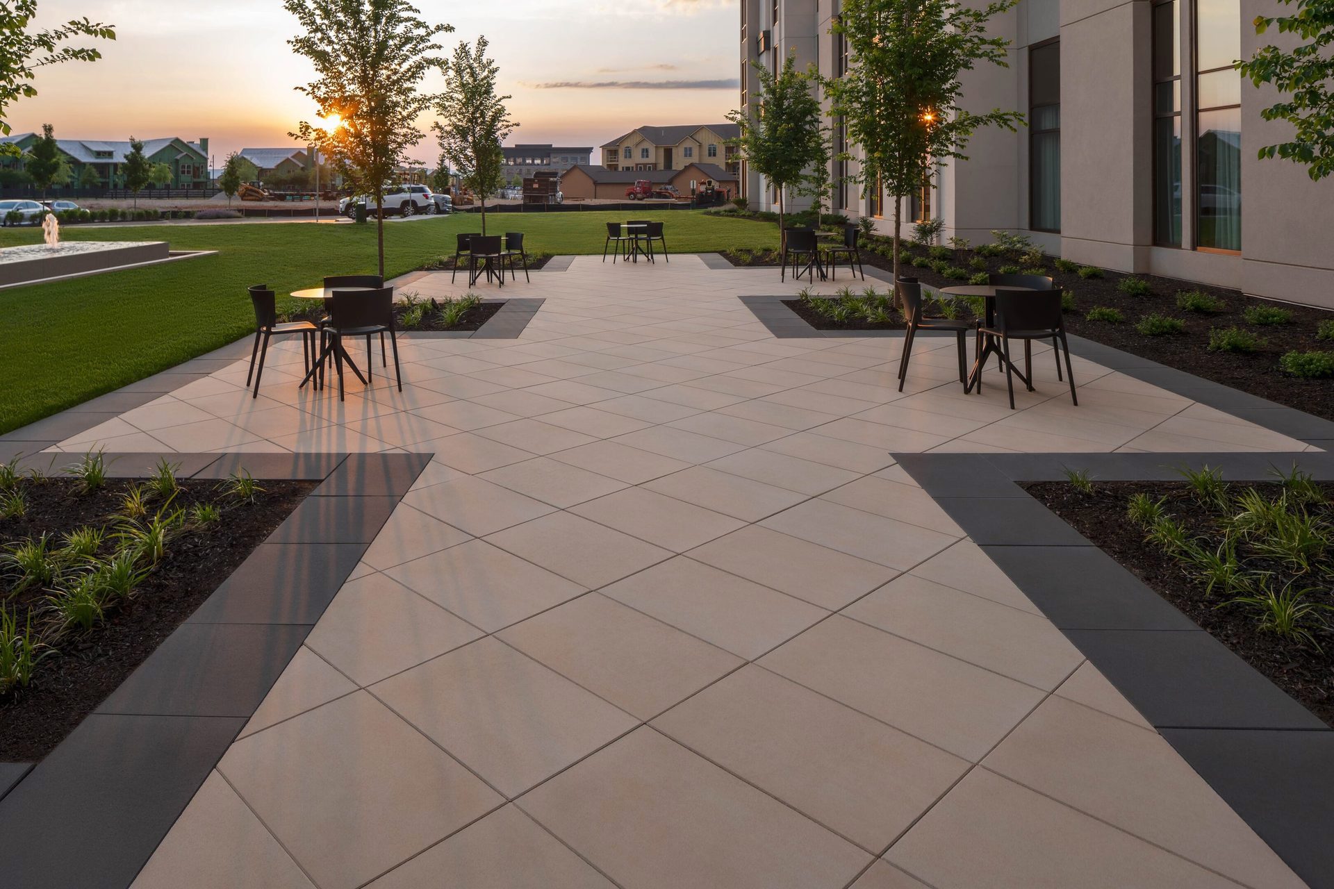 Angled view of the Embassy Suite Hotel courtyard with tables and chairs, featuring Techo-Bloc Para Commercial Slab in Onyx Black and Beige Cream.
